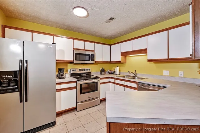 a kitchen with granite countertop a refrigerator stove and sink