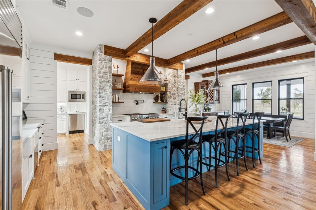 2577 Lone Star Road Celina, TX 75009 - Photo 6 of 40 a kitchen with stainless steel appliances granite countertop a stove oven a dining table and chairs with wooden floor