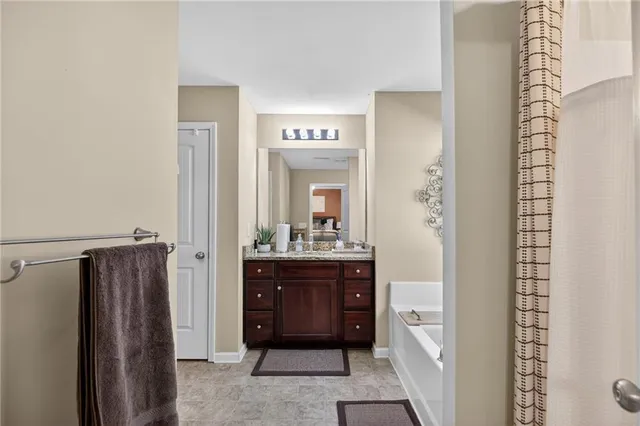 a bathroom with a granite countertop tub sink and mirror
