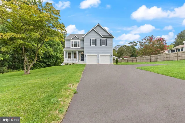 a view of a house next to a big yard and large trees
