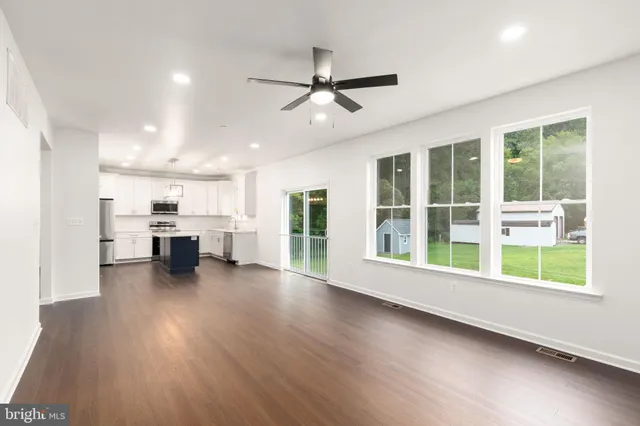 a view of an empty room with a kitchen and wooden floor