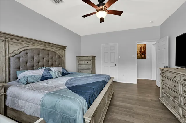 a bedroom with a large bed and a flat tv screen on dresser