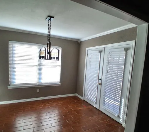 a view of an empty room with wooden floor kitchen view and a window
