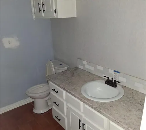 a bathroom with a granite countertop toilet a sink and a mirror