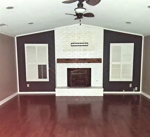 a view of wooden floor fire place and windows in a room