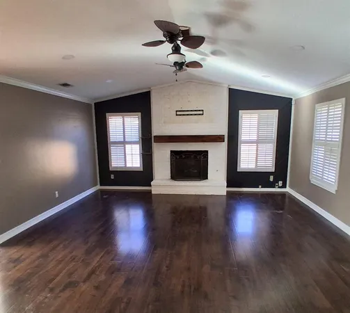 an empty room with wooden floor fireplace and windows