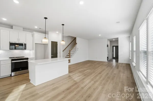 a large kitchen with granite countertop a large counter top a sink stainless steel appliances and cabinets