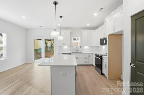 a kitchen with stainless steel appliances granite countertop cabinets a sink a center island and a window
