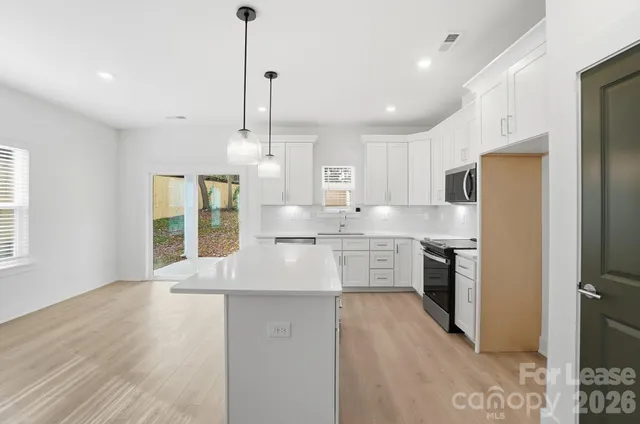 a kitchen with stainless steel appliances granite countertop cabinets a sink a center island and a window