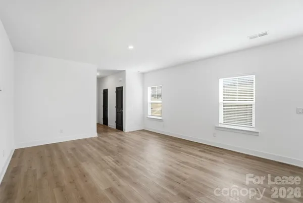 a view of an empty room with wooden floor and windows