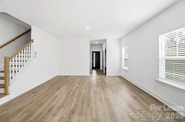 a view of an empty room with wooden floor and stairs