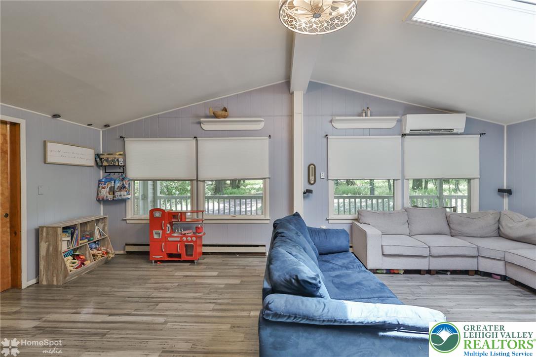 60 Sassafras Road Lehighton, PA 18235 - Photo 20 of 36 Natural light filters into this inviting family room, showcasing durable flooring and vaulted ceilings.