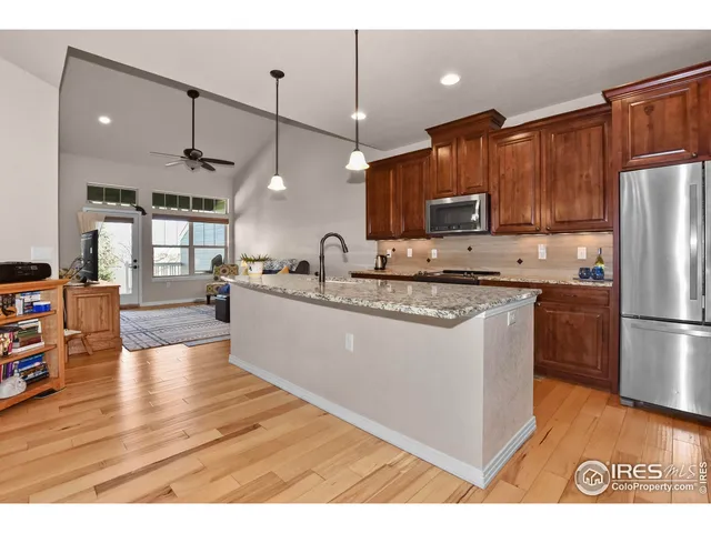 a kitchen with stainless steel appliances granite countertop a refrigerator a sink dishwasher a stove and a refrigerator with wooden floor