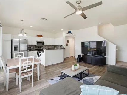 a living room with furniture kitchen view and a wooden floor
