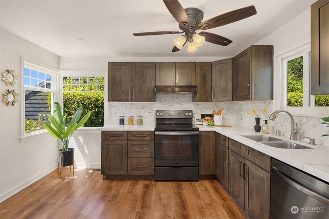 a kitchen with stainless steel appliances granite countertop a sink a stove a refrigerator cabinets and wooden floor