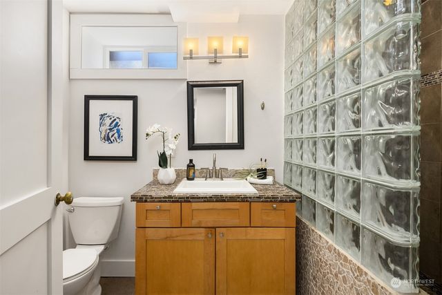 a bathroom with a granite countertop sink mirror vanity and toilet