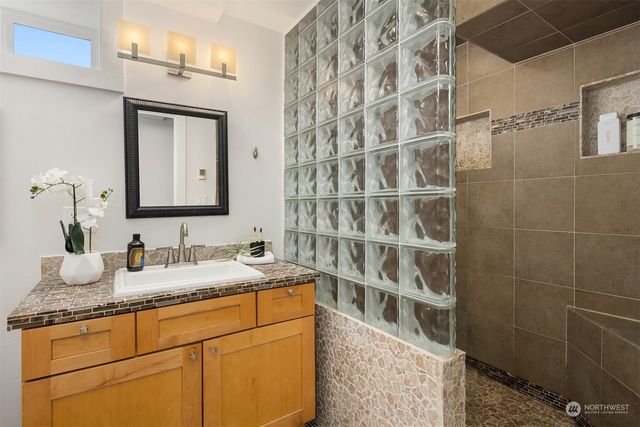 a bathroom with a granite countertop sink a mirror and shower