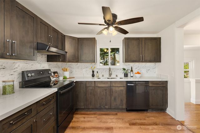 a kitchen with stainless steel appliances granite countertop a sink a stove top oven and cabinetry