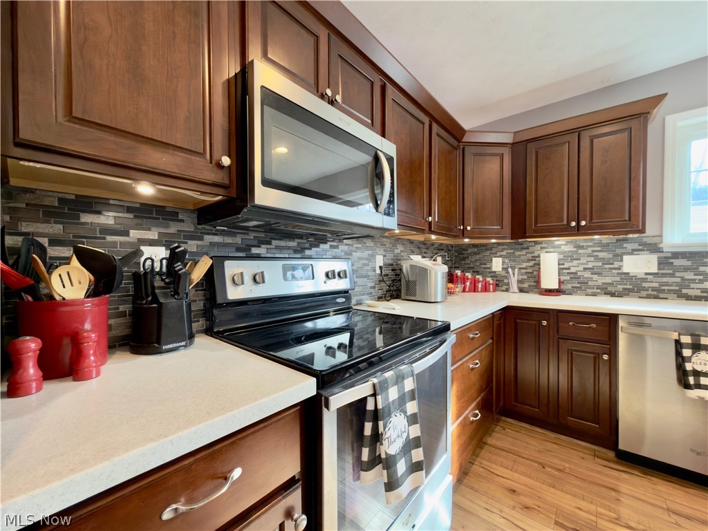 17377 Murphy Road Amesville, OH 45711 - Photo 4 of 43 Kitchen with stainless steel appliances, light wood finished floors, decorative backsplash, and dark wood finish cabinets