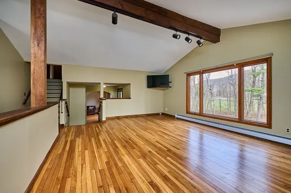 a view of empty room with wooden floor and fan