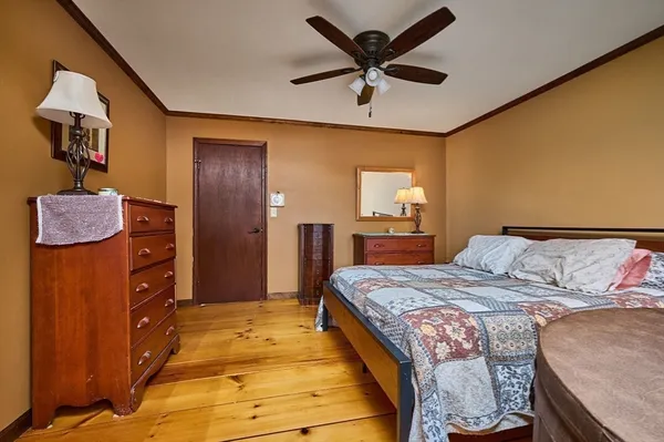 a bedroom with a bed a dresser and a chandelier