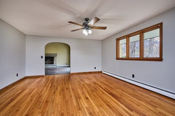 a view of empty room with wooden floor and fan
