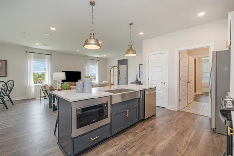 a kitchen with stainless steel appliances a dining table chairs and wooden floor