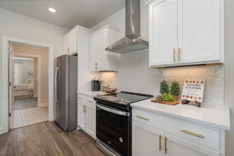 a large kitchen with kitchen island a stove a sink a refrigerator and a dining table with wooden floor
