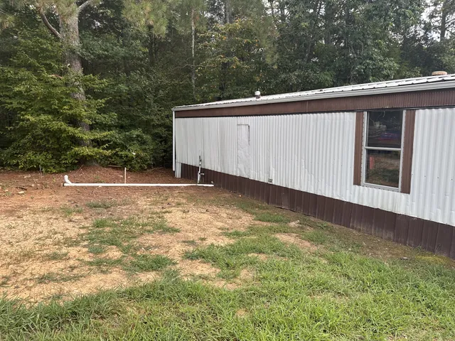 a view of a house with a yard and large trees