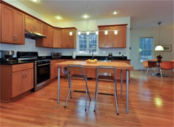 5 Squirrel Hill Road Acton, MA 01720 - Photo 13 of 30 a kitchen with stainless steel appliances granite countertop a stove top oven a sink a dining table and chairs with wooden floor