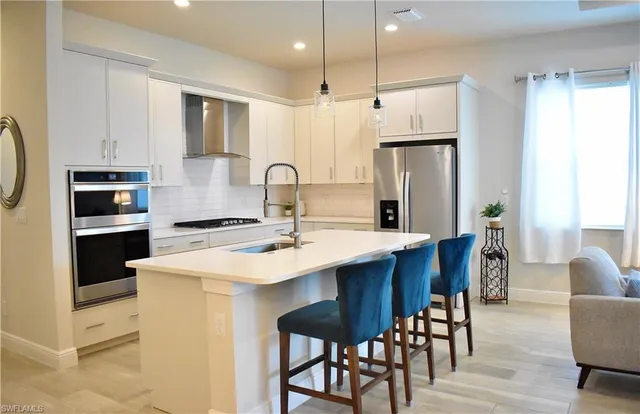 a kitchen with stainless steel appliances a table chairs refrigerator and microwave