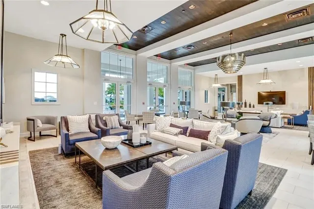 a living room with lots of furniture kitchen view and a chandelier