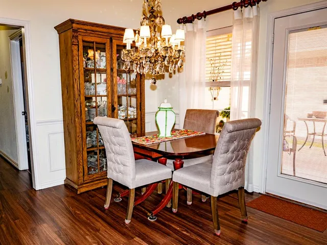 a kitchen with stainless steel appliances a stove top oven a refrigerator a dining table and chairs with wooden floor