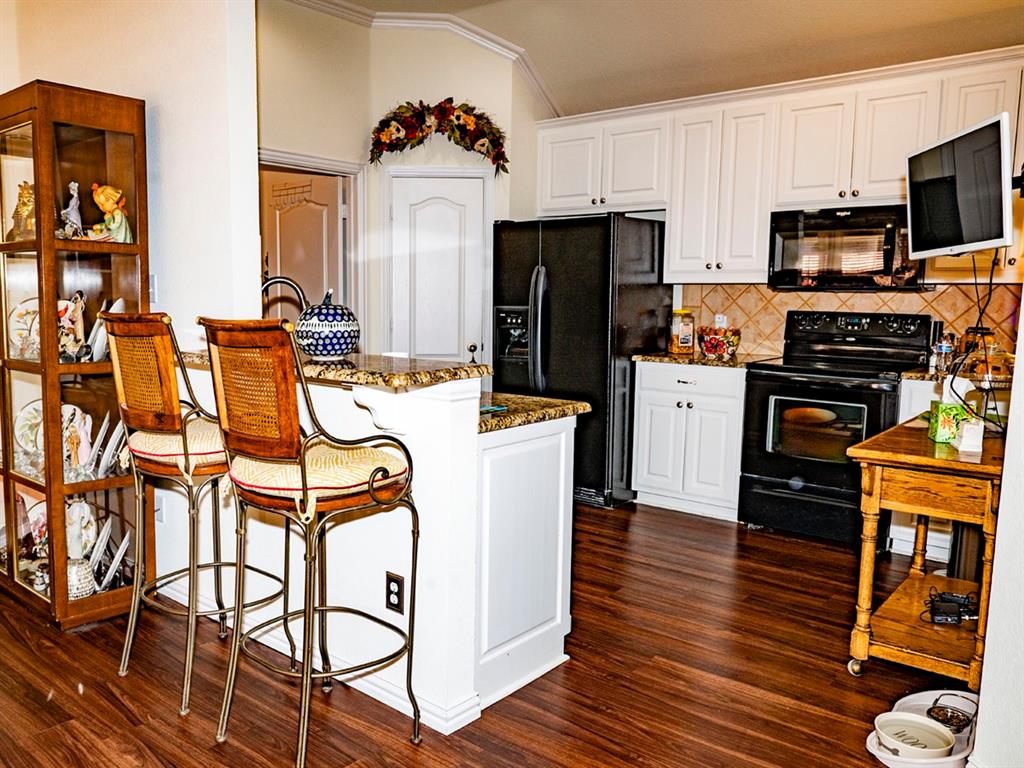 9028 Racquet Club Drive Fort Worth, TX 76120 - Photo 12 of 26 a kitchen with stainless steel appliances a stove top oven a refrigerator a dining table and chairs with wooden floor