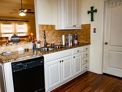 9028 Racquet Club Drive Fort Worth, TX 76120 - Photo 13 of 26 a kitchen with granite countertop white cabinets and a sink