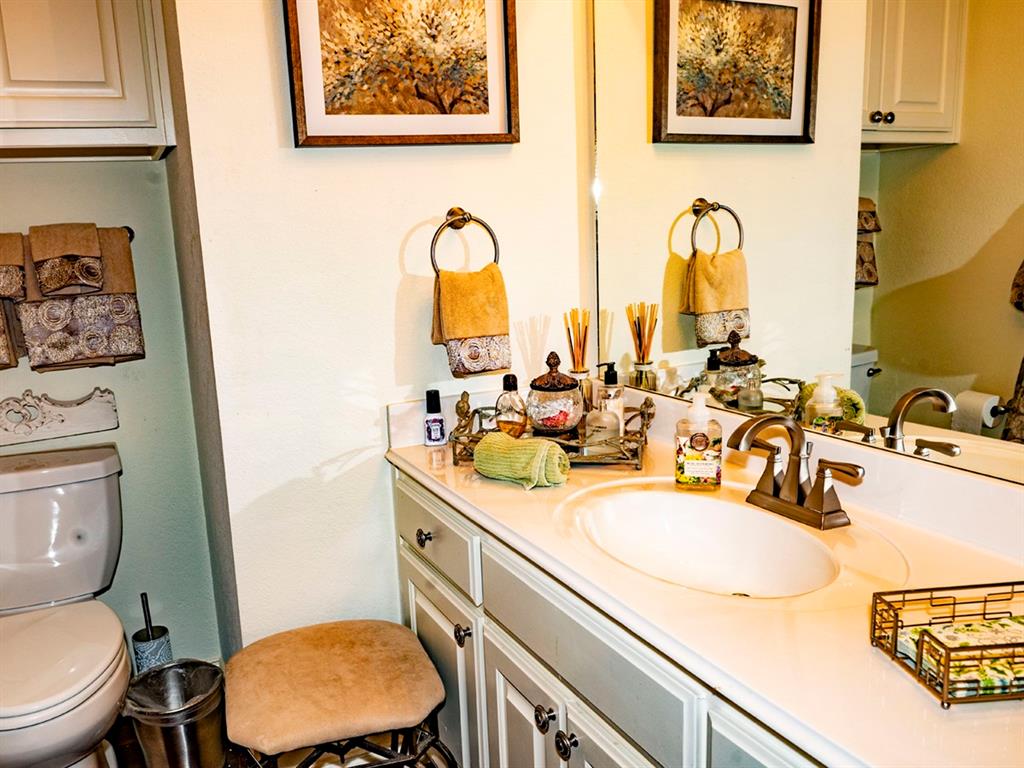 9028 Racquet Club Drive Fort Worth, TX 76120 - Photo 22 of 26 a bathroom with a sink mirror vanity and toilet