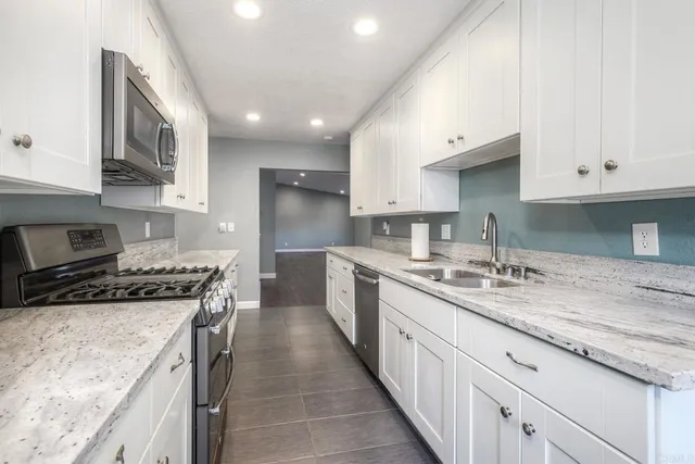 a kitchen with stainless steel appliances granite countertop a stove a sink and a refrigerator