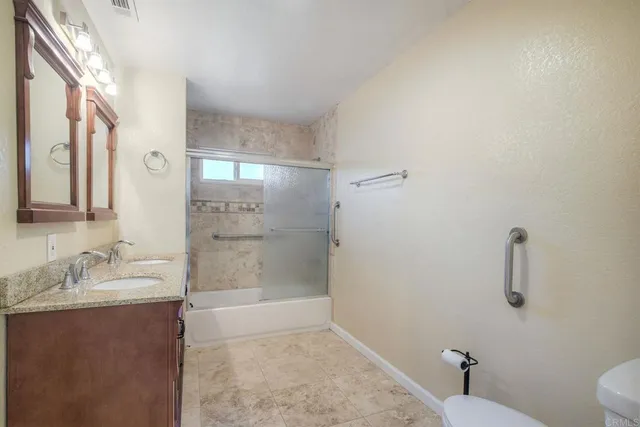 a bathroom with a granite countertop sink a toilet and shower