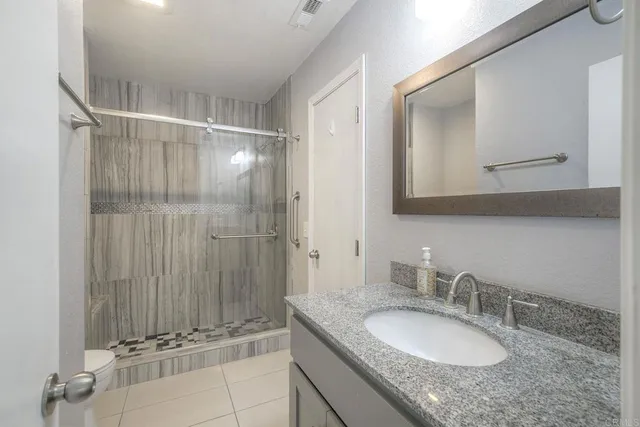 a bathroom with a granite countertop sink a mirror and shower