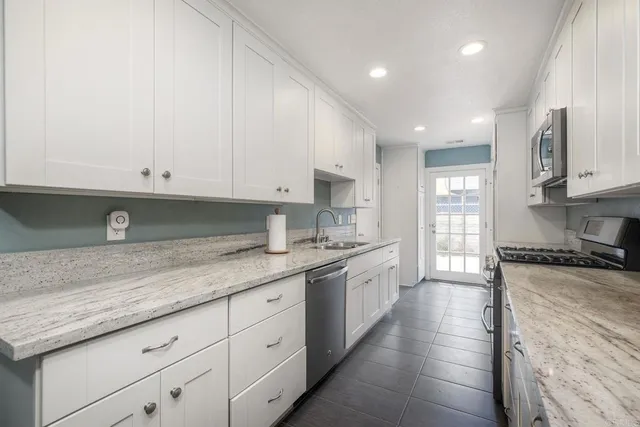 a kitchen with granite countertop white cabinets and stainless steel appliances