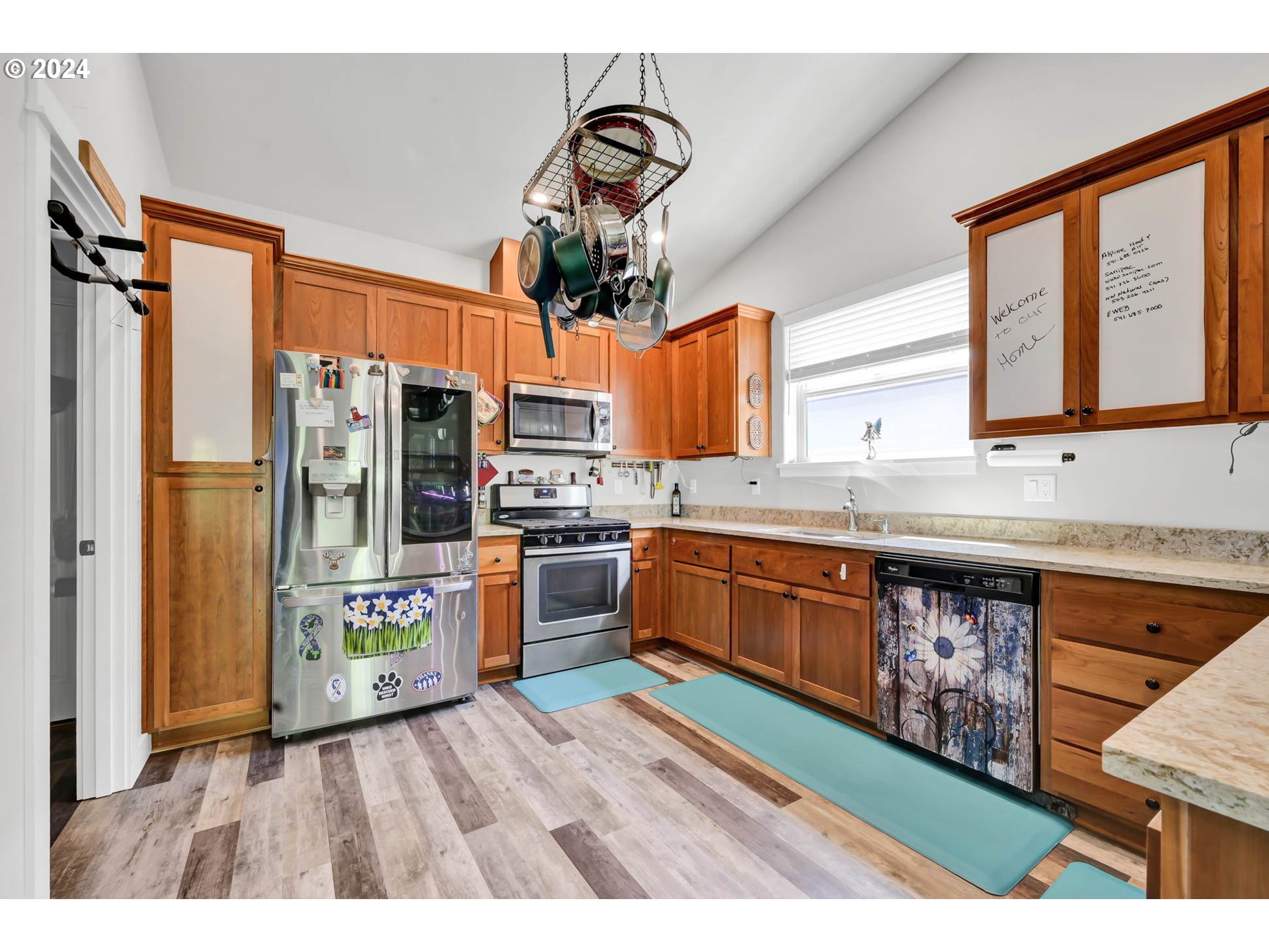 945 Pennington Court Eugene, OR 97404 - Photo 12 of 40 a kitchen with stainless steel appliances granite countertop a refrigerator a sink dishwasher a stove with wooden cabinets and floor