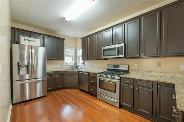 a kitchen with granite countertop wooden floors stainless steel appliances and a sink