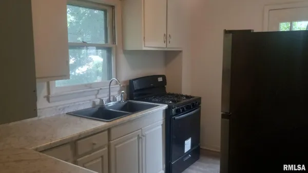 a kitchen with granite countertop a refrigerator stove and sink