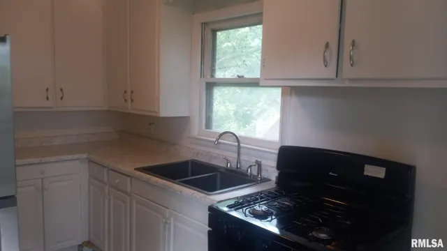 a kitchen with granite countertop a sink stove and cabinets