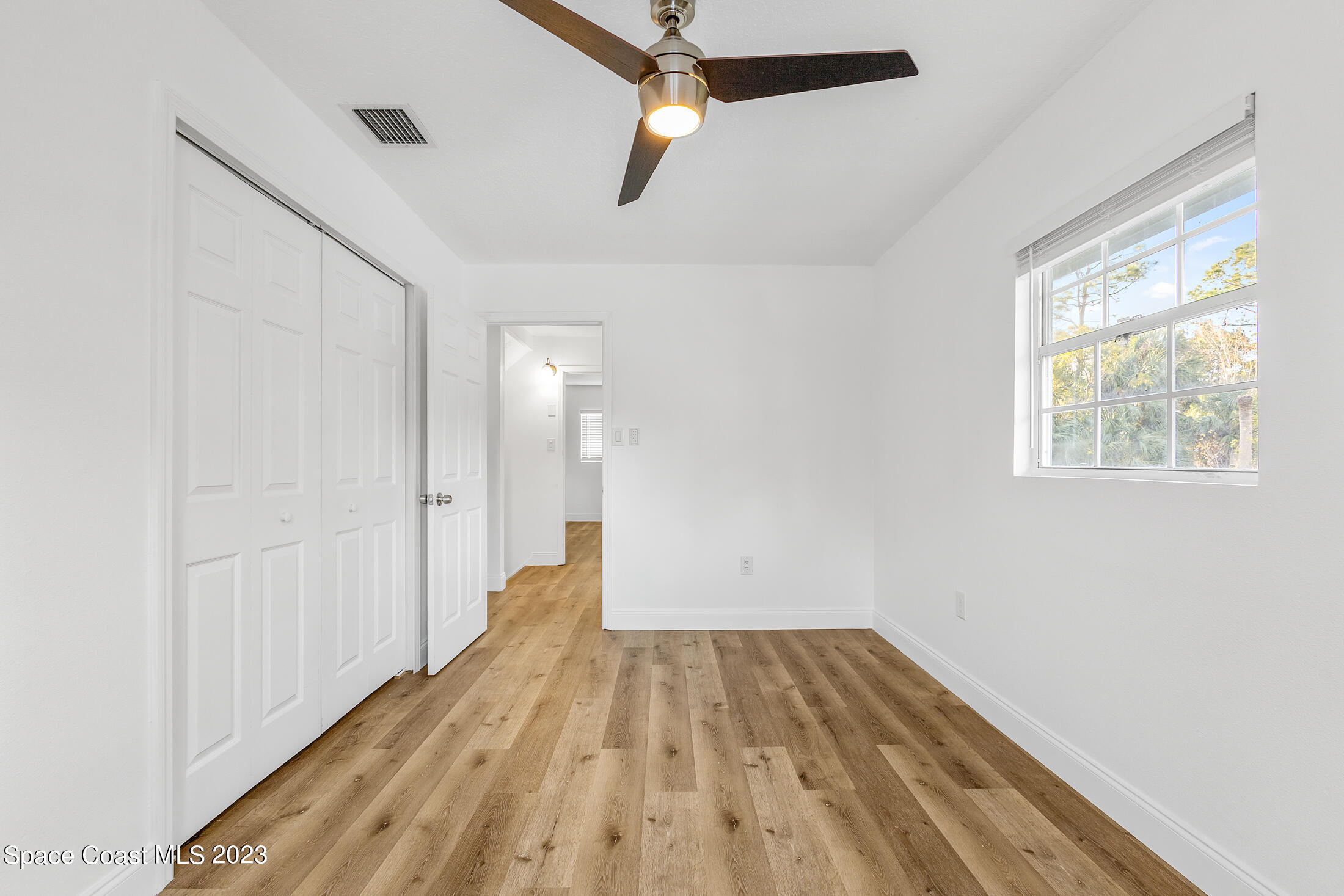 2300 Cox Road Cocoa, FL 32926 - Photo 22 of 41 a view of a room with wooden floor closet and a ceiling fan