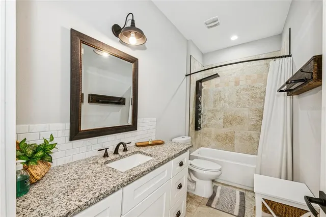 a bathroom with a granite countertop sink a toilet and shower