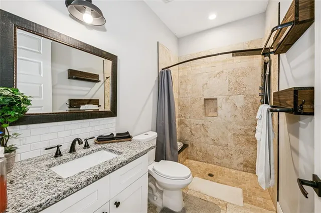 a bathroom with a granite countertop sink toilet mirror and shower