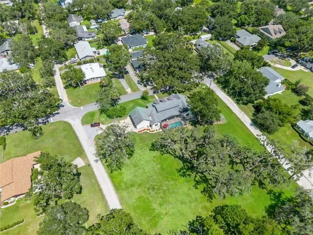an aerial view of residential house with outdoor space and trees all around