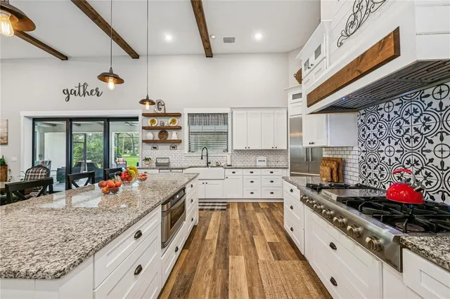 a kitchen with stainless steel appliances granite countertop a stove a sink dishwasher and cabinets with wooden floor