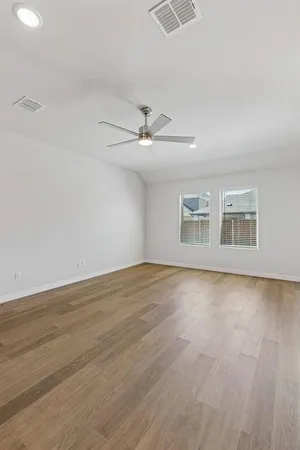 an empty room with wooden floor chandelier fan and windows